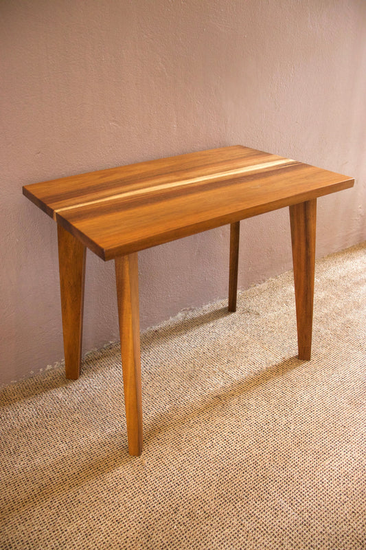 Wooden table with a striped design on a textured floor and wall.