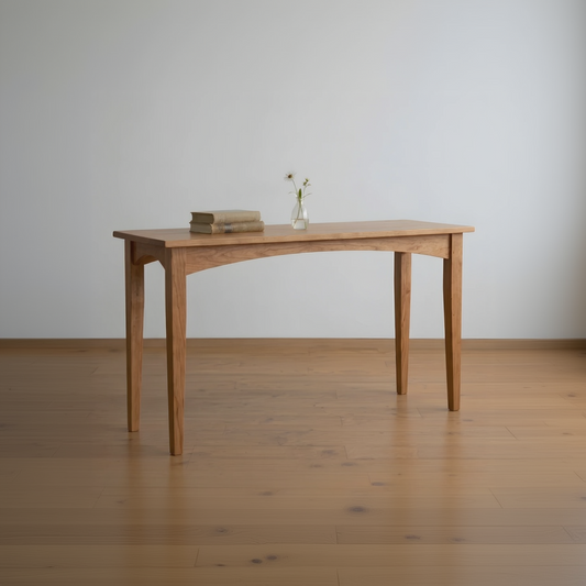 Wooden desk with a vase and books on a wooden floor against a white wall